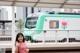 A woman standing in front of a green and white train.