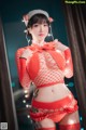 A woman in a red fishnet outfit holding a string of lights.