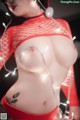 A woman in a red fishnet top is posing for the camera.