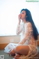 A woman in a white lace robe sitting on the floor.