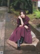 A woman sitting on a stone bench in a park.