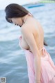 A woman in a pink dress standing in the water.