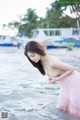 A woman in a pink dress standing in the water.