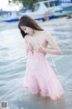 A woman in a pink dress standing in the water.