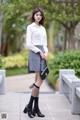 A woman in a white shirt and gray skirt posing for a picture.