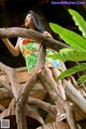 A woman in a colorful dress leaning against a wooden structure.