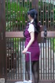 A woman in a purple dress with a suitcase.