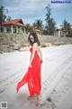 A woman in a red dress walking on the beach.