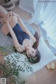 A woman laying on a bed in a blue bathing suit.