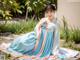 A woman in a blue and pink hanbok sitting on the ground.