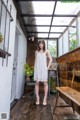 A woman in a white dress standing on a wooden floor.