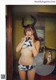 A woman in a cow print bikini with horns on her head.