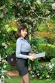 A woman in a blue shirt and black skirt holding a folder.