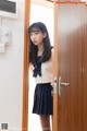 A young woman in a school uniform standing in front of a door.