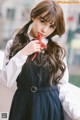 A young woman in a school uniform holding a red ribbon.