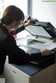 A woman is using a printer in an office.