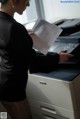 A woman in a business suit is using a printer.