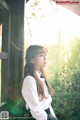 A woman in a white shirt and black skirt leaning against a wooden fence.