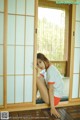 A woman sitting on the floor in front of a sliding glass door.