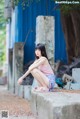 A woman sitting on a concrete ledge in front of a blue building.