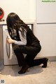 A woman crouching down in front of a washing machine.