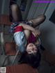 A woman laying on top of a desk in a classroom.