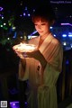 A woman in a bathrobe holding a bowl of candles.