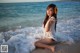 A woman sitting on the beach with a flower in her hair.