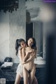 Two naked women standing next to each other in a bathroom.