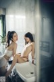 A couple of women sitting on top of a bathroom sink.