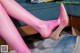 A close up of a woman's legs wearing pink tights and high heels.