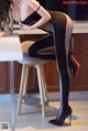 A woman sitting on top of a stool in a kitchen.