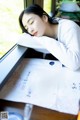 A woman sleeping on a table next to a window.