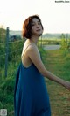 A woman in a blue dress standing in a field.