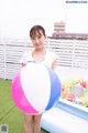 A woman holding a large pink and blue beach ball.