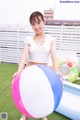 A woman holding a large beach ball on top of a green field.