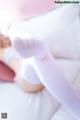 A woman in white stockings laying on a bed.