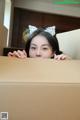 A young woman peeking over a cardboard box.