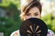 A woman holding a black fan in front of her face.