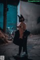 A woman wearing a cat mask standing in an alleyway.