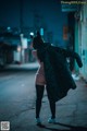 A woman in a black coat is walking down the street.