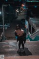 A woman wearing a mask standing on a stairway at night.