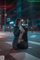 A woman wearing a mask sitting on the street at night.