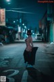 A woman in a black dress is standing in the middle of the street.