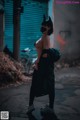 A woman wearing a cat mask standing in an alleyway.