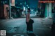 A woman wearing a mask standing in the middle of a street.