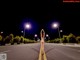 A naked woman standing in the middle of a road at night.