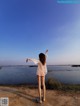 A woman standing on a beach with her arms outstretched.