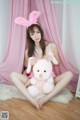 A woman in bunny ears sitting on the floor holding a stuffed animal.