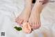 A woman's feet with a rose on a bed.